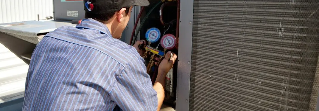 HVAC technician servicing a condenser unit in Uxbridge
